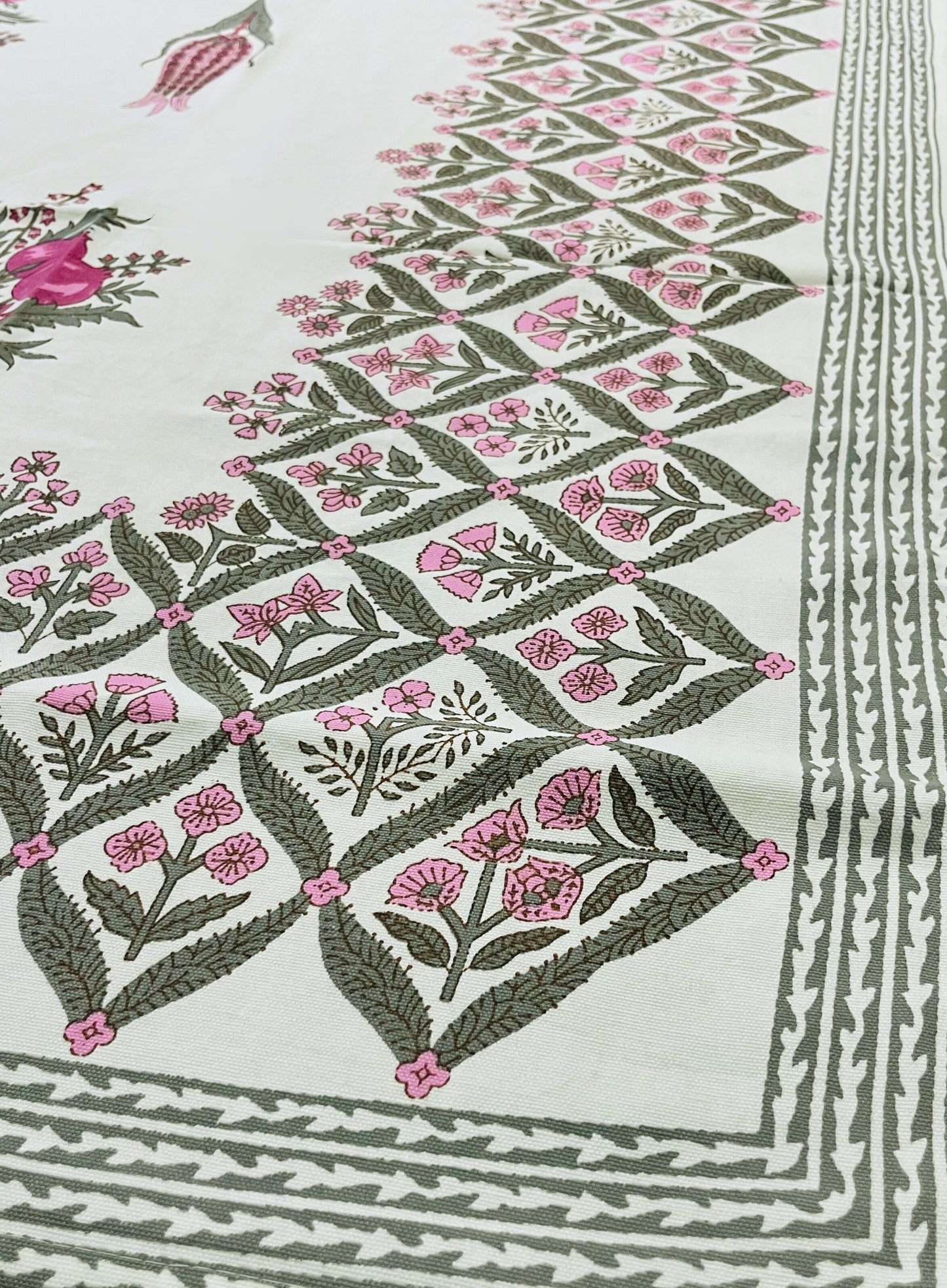 Close-up of floral block print tablecloth featuring a traditional pink and green design on a white cotton fabric
