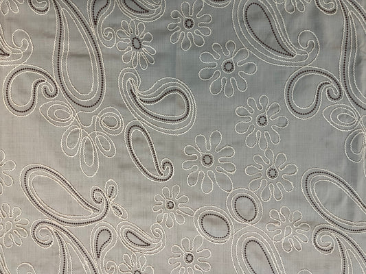 Close-up of decorative table cover showcasing delicate floral paisley embroidery on a soft and textured fabric base