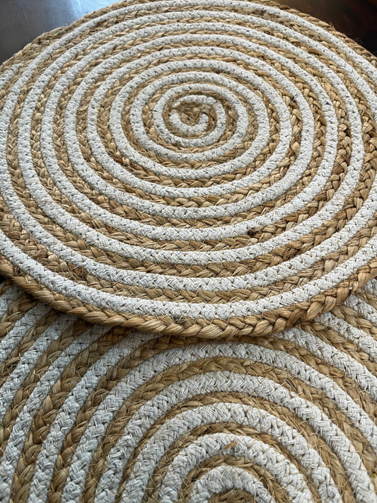 Close-up of round braided jute placemat showcasing natural fiber texture and white spiral pattern