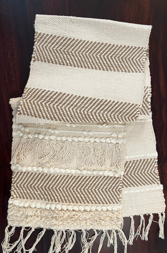 Beautifully styled dining table with a decorative table runner featuring pom poms and tassels