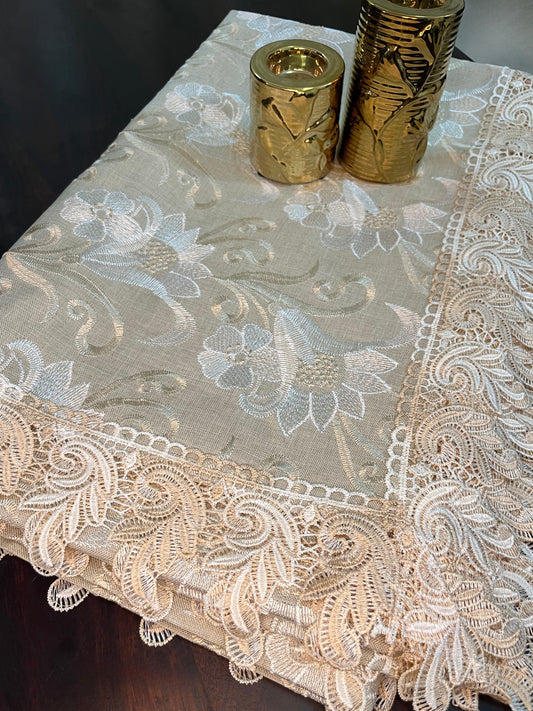 Beautifully styled dining table featuring an elegant lace tablecloth with gold and white floral embroidery and a scalloped border
