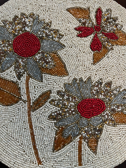 Close-up of handcrafted table mat showcasing delicate beadwork in a grey and red floral design