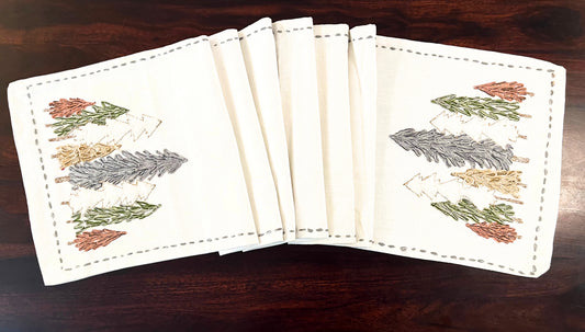 Close-up of decorative table runner showcasing embroidered pine trees with fine detailing