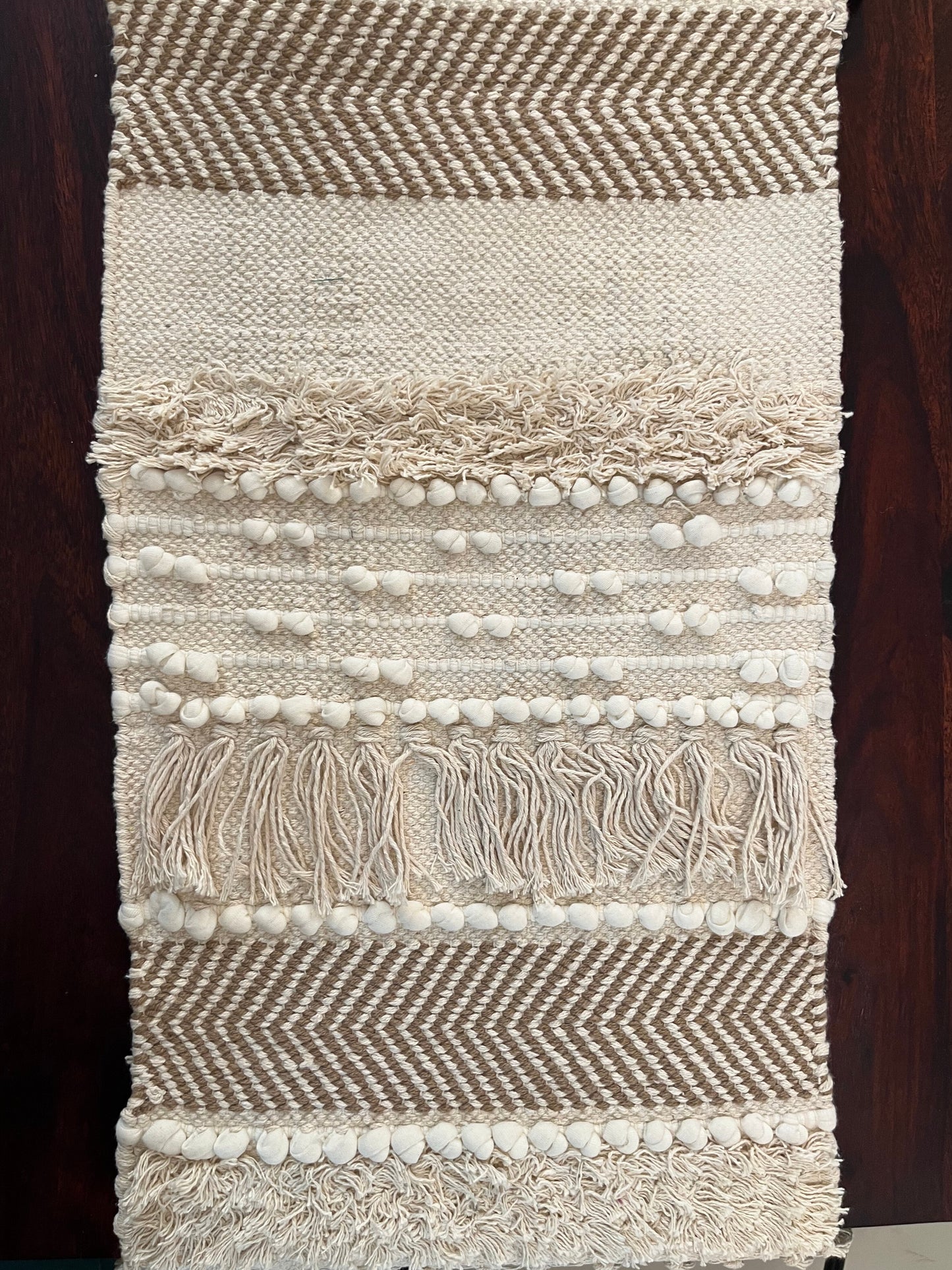 Close-up of decorative table runner showcasing intricate pom poms and tassels