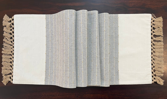 Angled view of decorative table runner showcasing tassel accents and intricate embroidery in gray and white