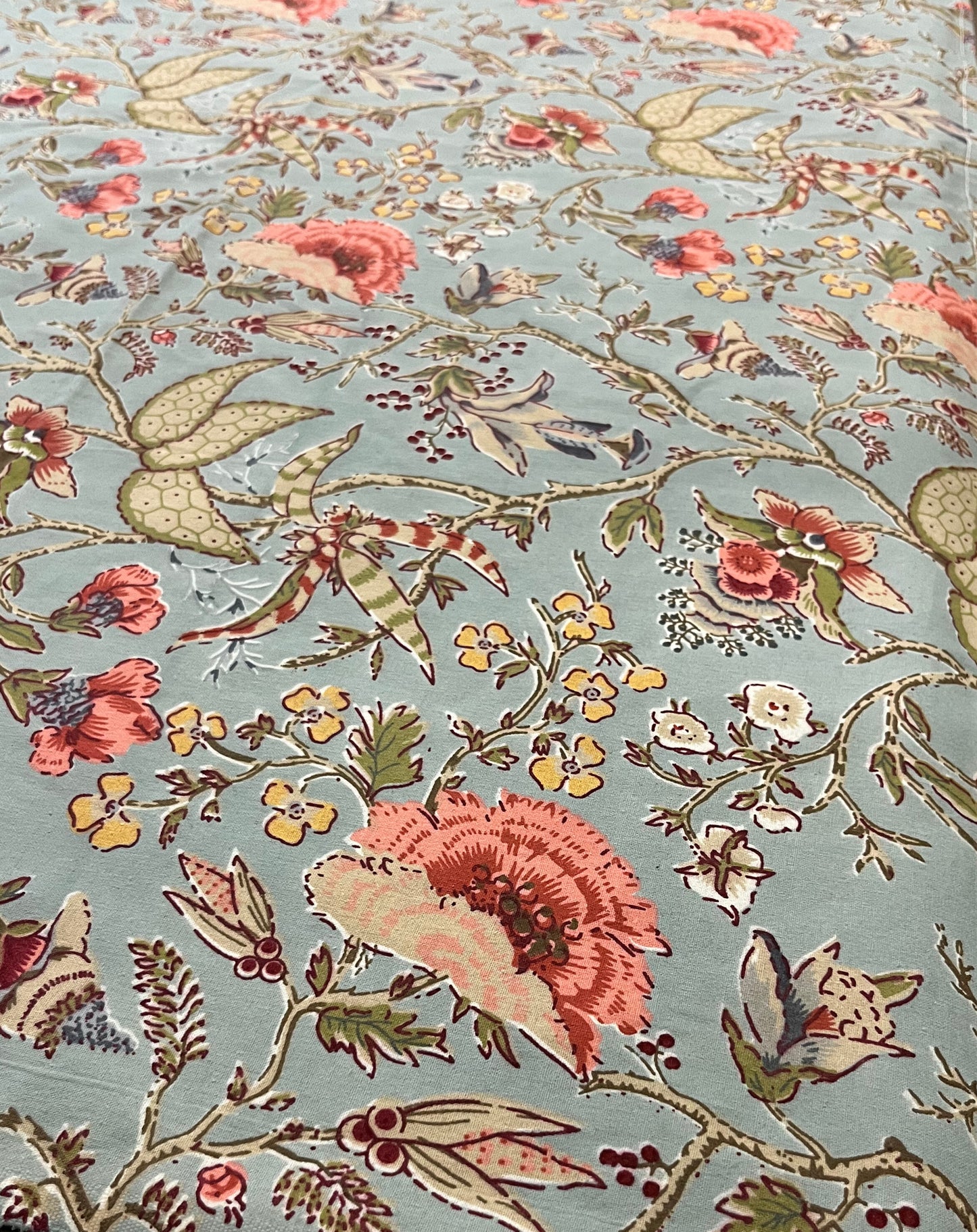Close-up of floral dining tablecloth showcasing a vintage botanical print in blue-green with coral flowers