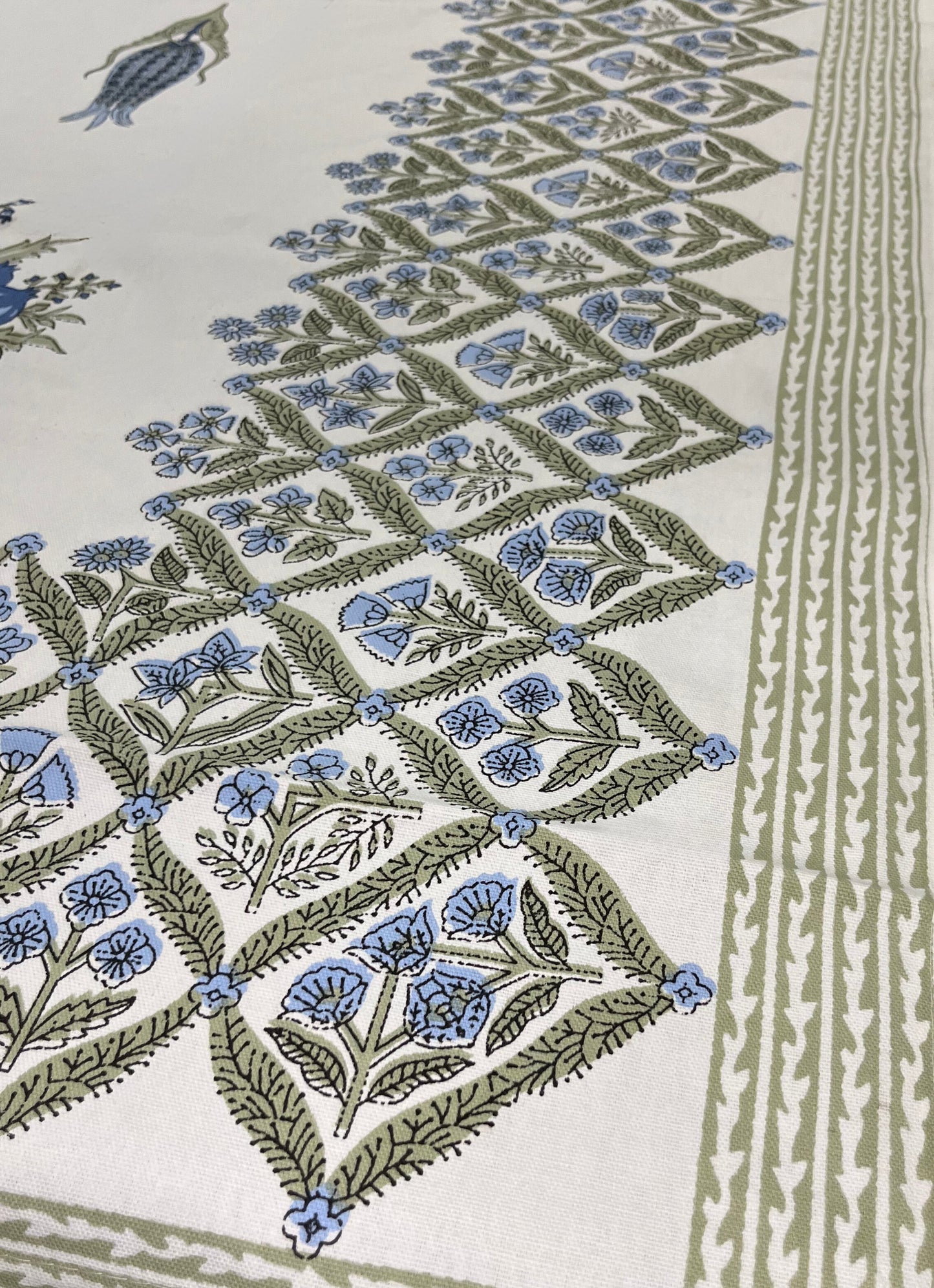 Close-up of floral block print tablecloth featuring a traditional blue and green design on a white cotton fabric