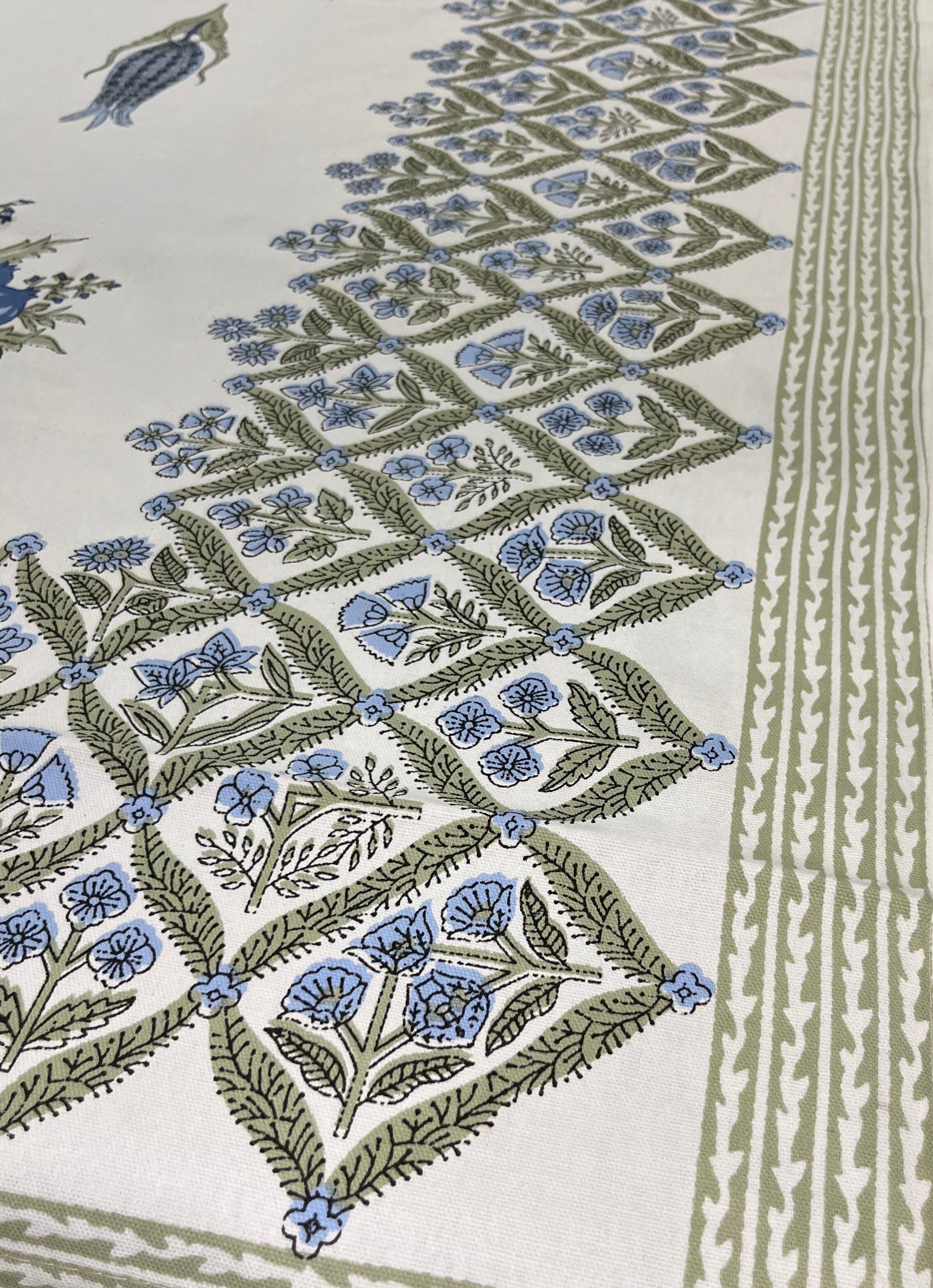 Close-up of floral block print tablecloth featuring a traditional blue and green design on a white cotton fabric