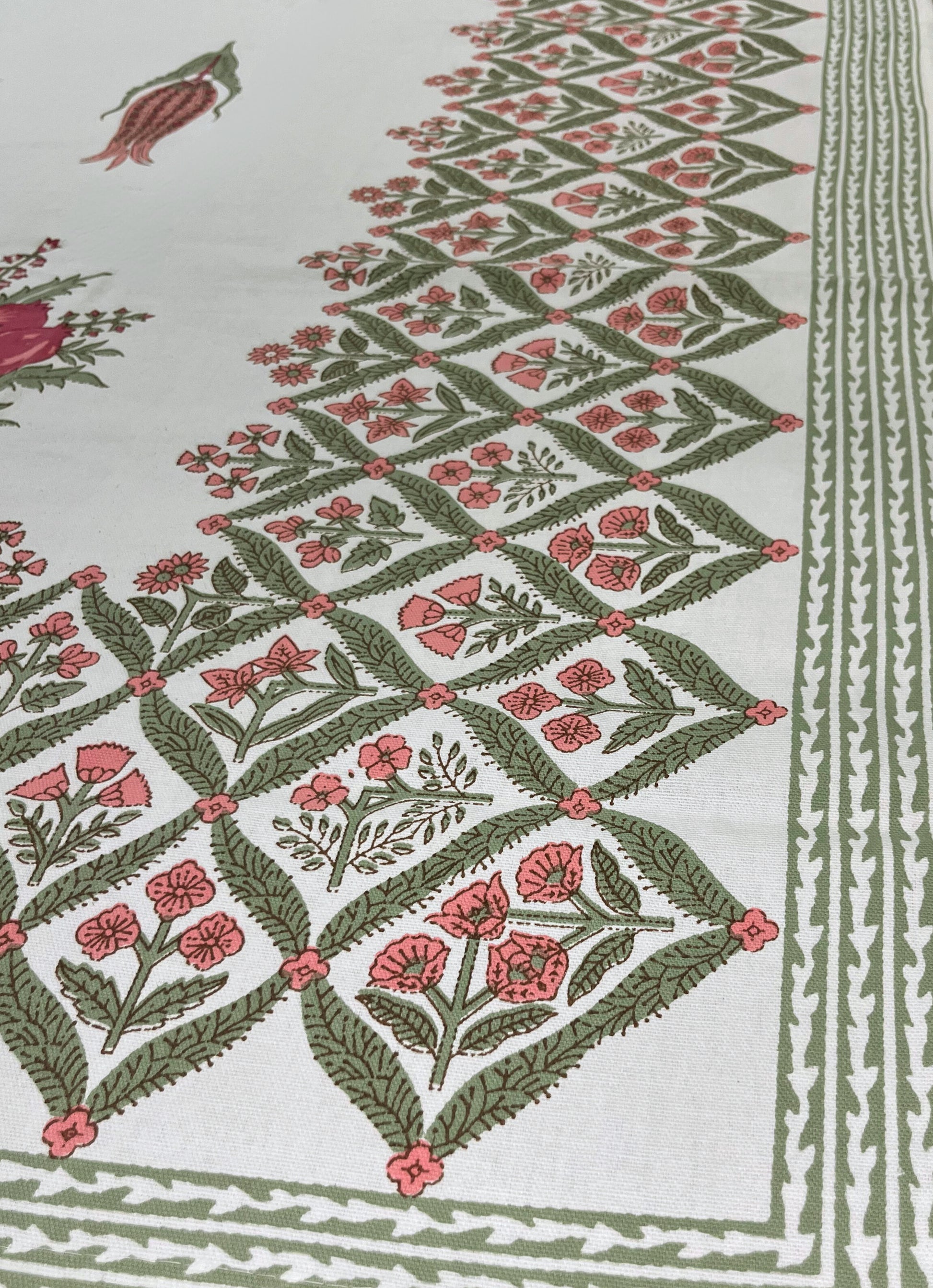 Close-up of floral block print tablecloth featuring a traditional red and green design on a white cotton fabric