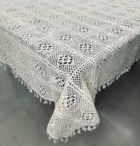 Crocheted dining tablecloth with a diamond pattern and tassels in a soft cream color