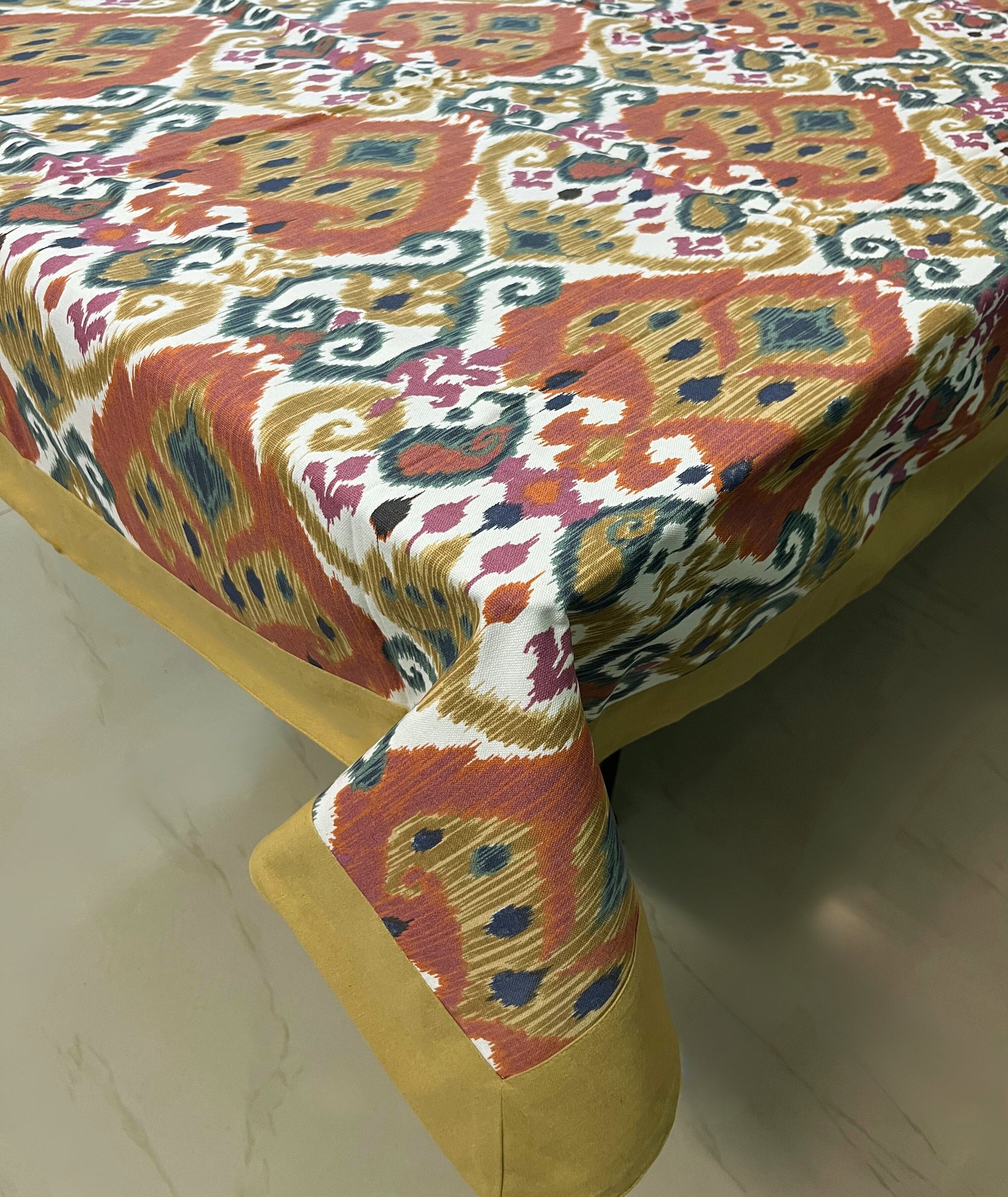 Decorative dining tablecloth with an Ikat pattern, gold border, and a modern boho design