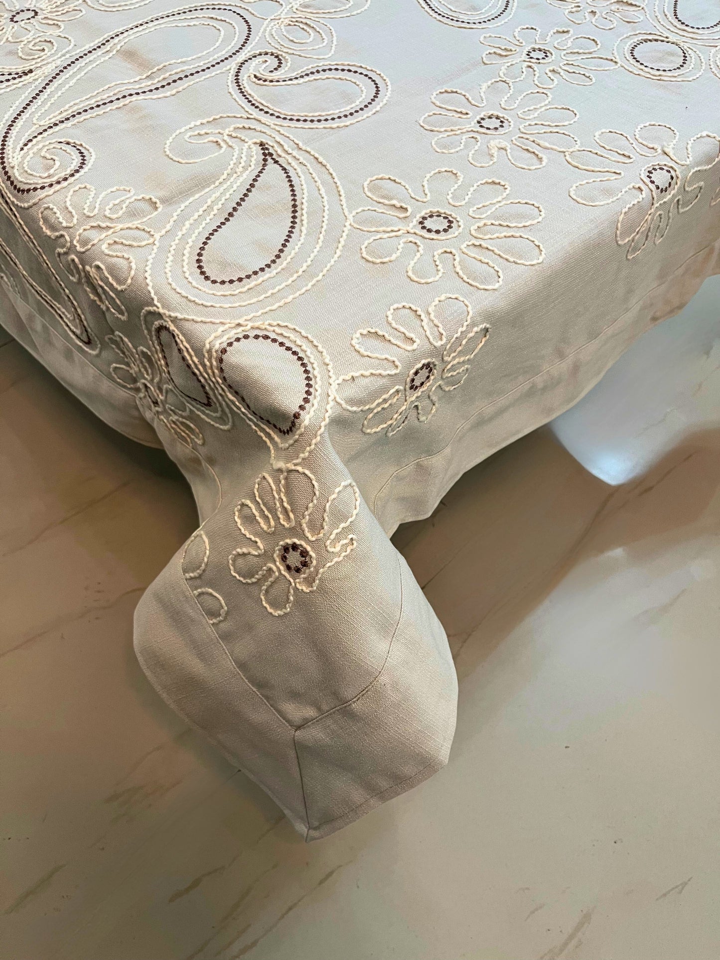 Decorative table cover featuring intricate floral paisley embroidery, adding a touch of elegance to any dining space