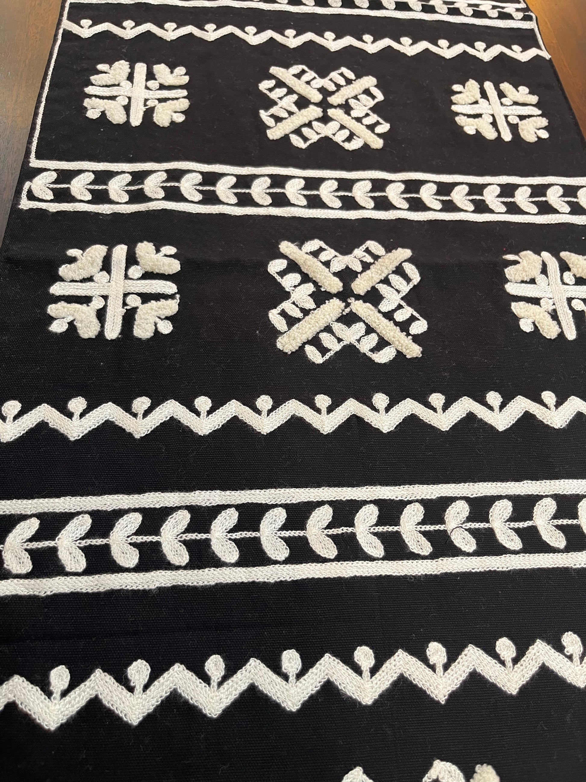 Decorative table runner featuring geometric folk embroidery in black and white for a modern touch