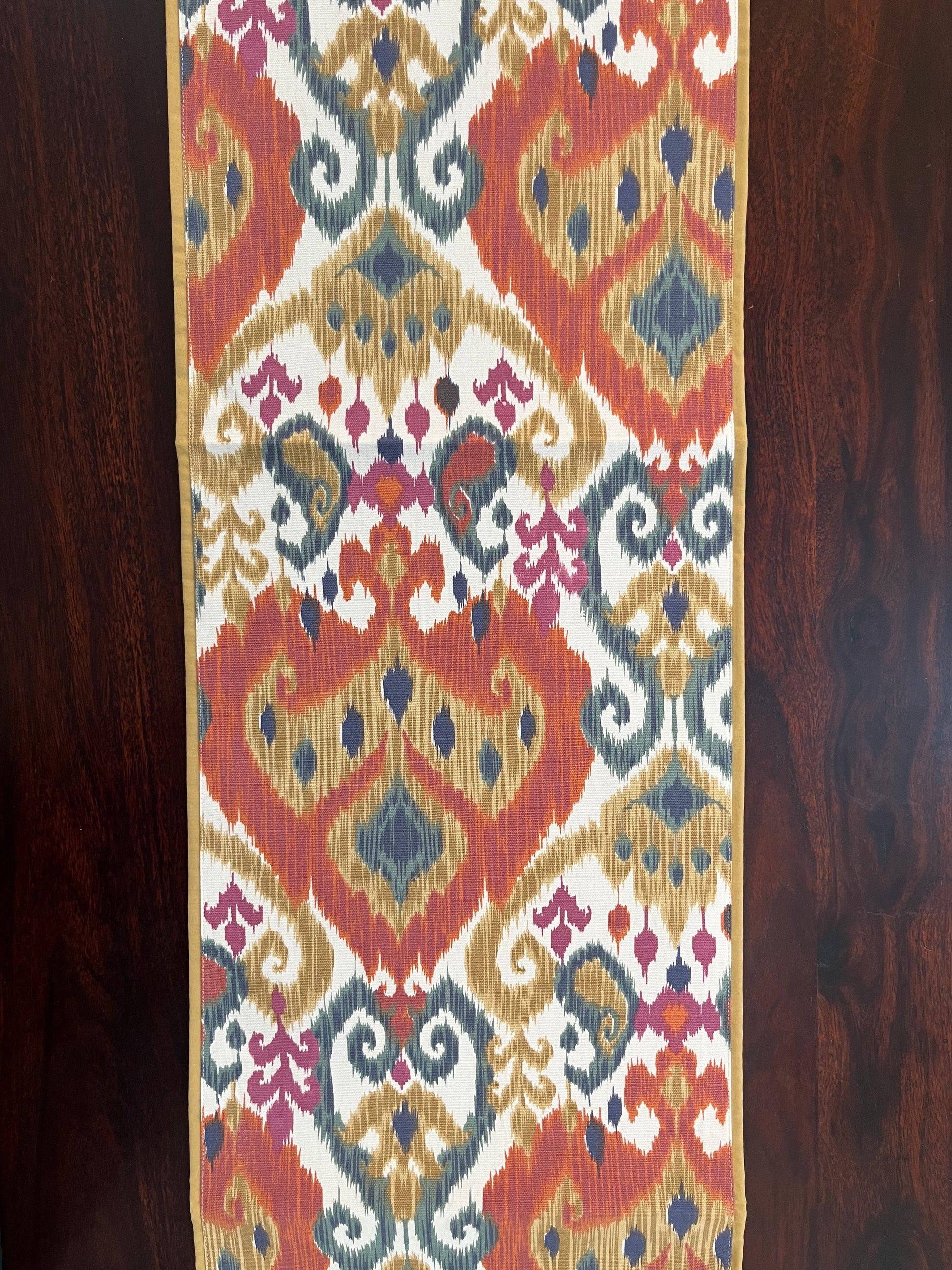 Decorative table runner featuring an Ikat pattern with a multicolour boho design in orange and blue