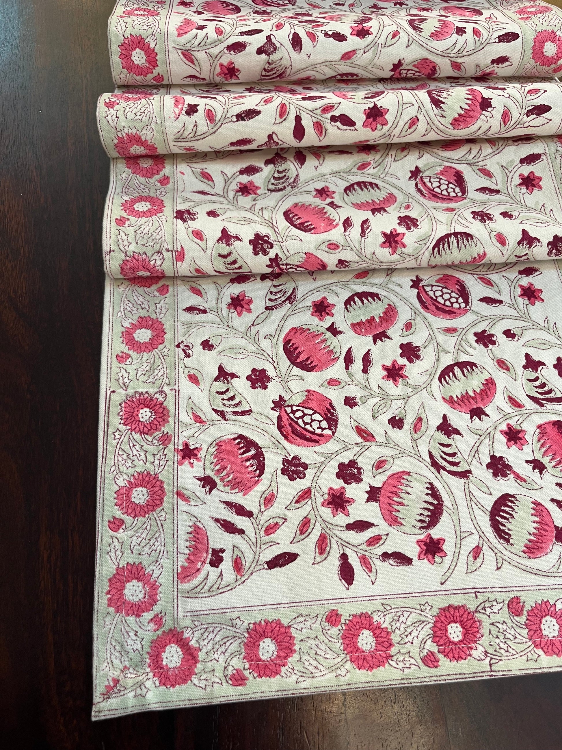 Decorative table runner featuring a pomegranate floral pattern in pink and white