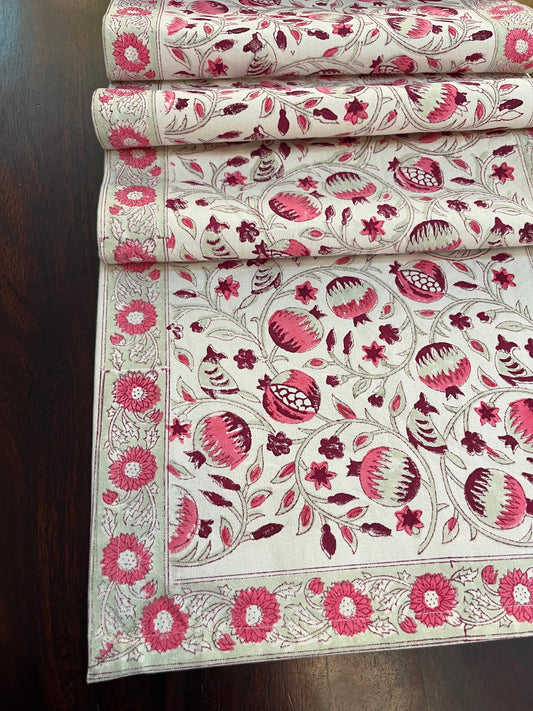 Decorative table runner featuring a pomegranate floral pattern in pink and white