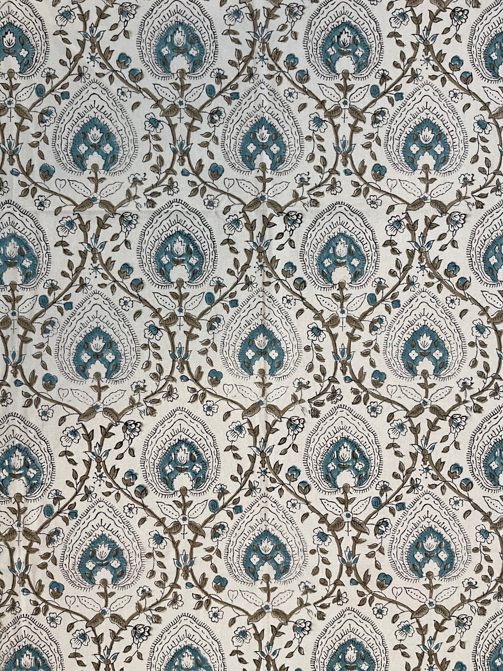 Close-up of cotton tablecloth showcasing intricate floral and geometric designs in teal and beige on a soft fabric base
