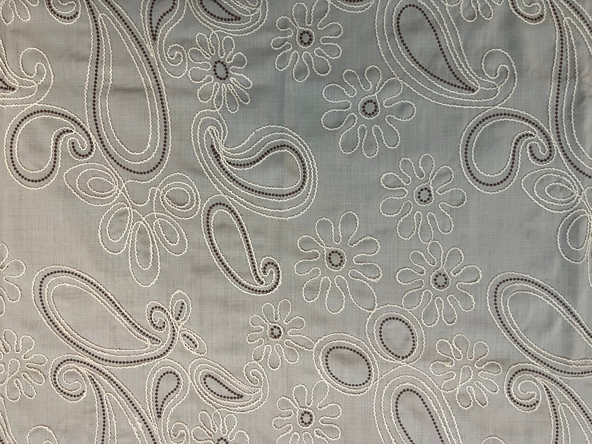 Close-up of decorative table cover showcasing delicate floral paisley embroidery on a soft and textured fabric base