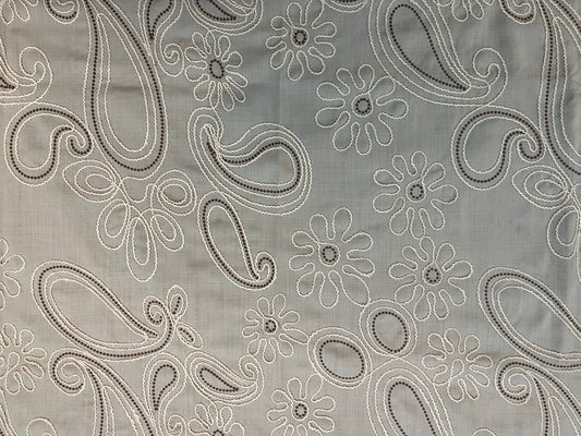 Close-up of decorative table cover showcasing delicate floral paisley embroidery on a soft and textured fabric base