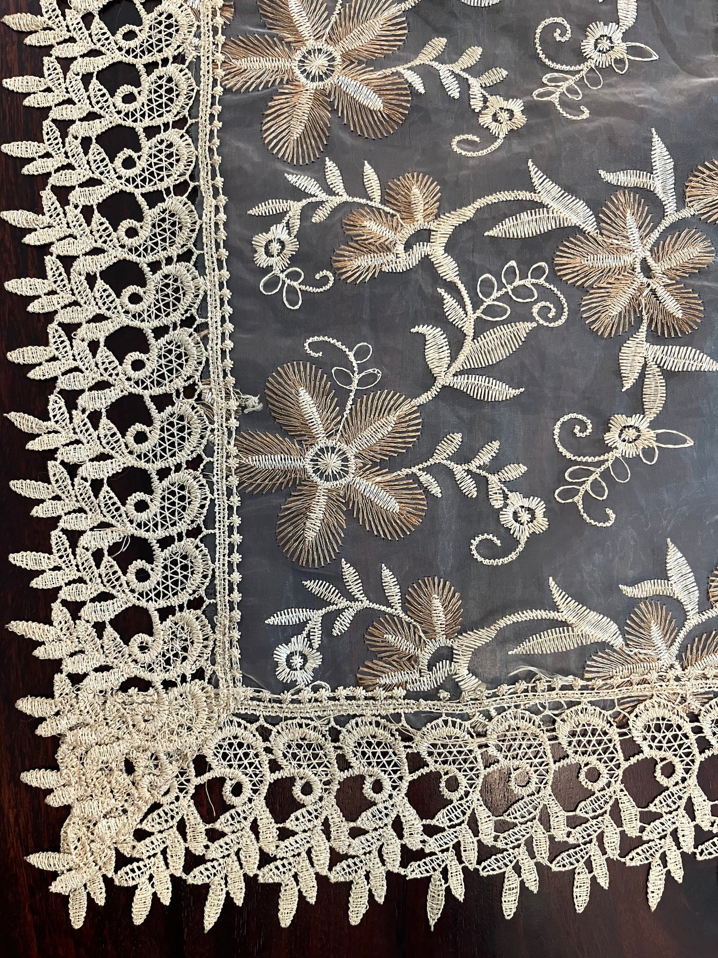 Close-up of vintage lace table runner showcasing delicate floral embroidery and scalloped edges