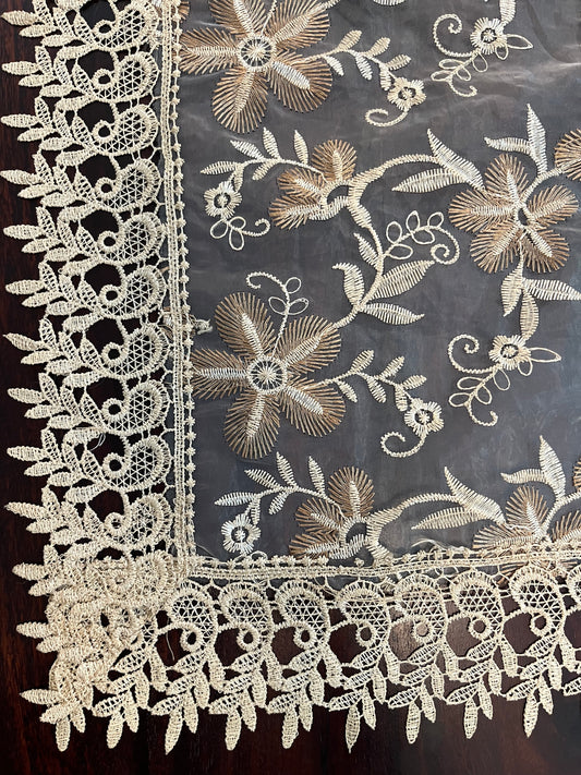 Close-up of vintage lace table runner showcasing delicate floral embroidery and scalloped edges