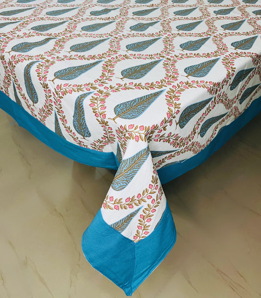 Floral block print cotton dining table cover in blue and white with pink flowers and a traditional leaf pattern with a turquoise border