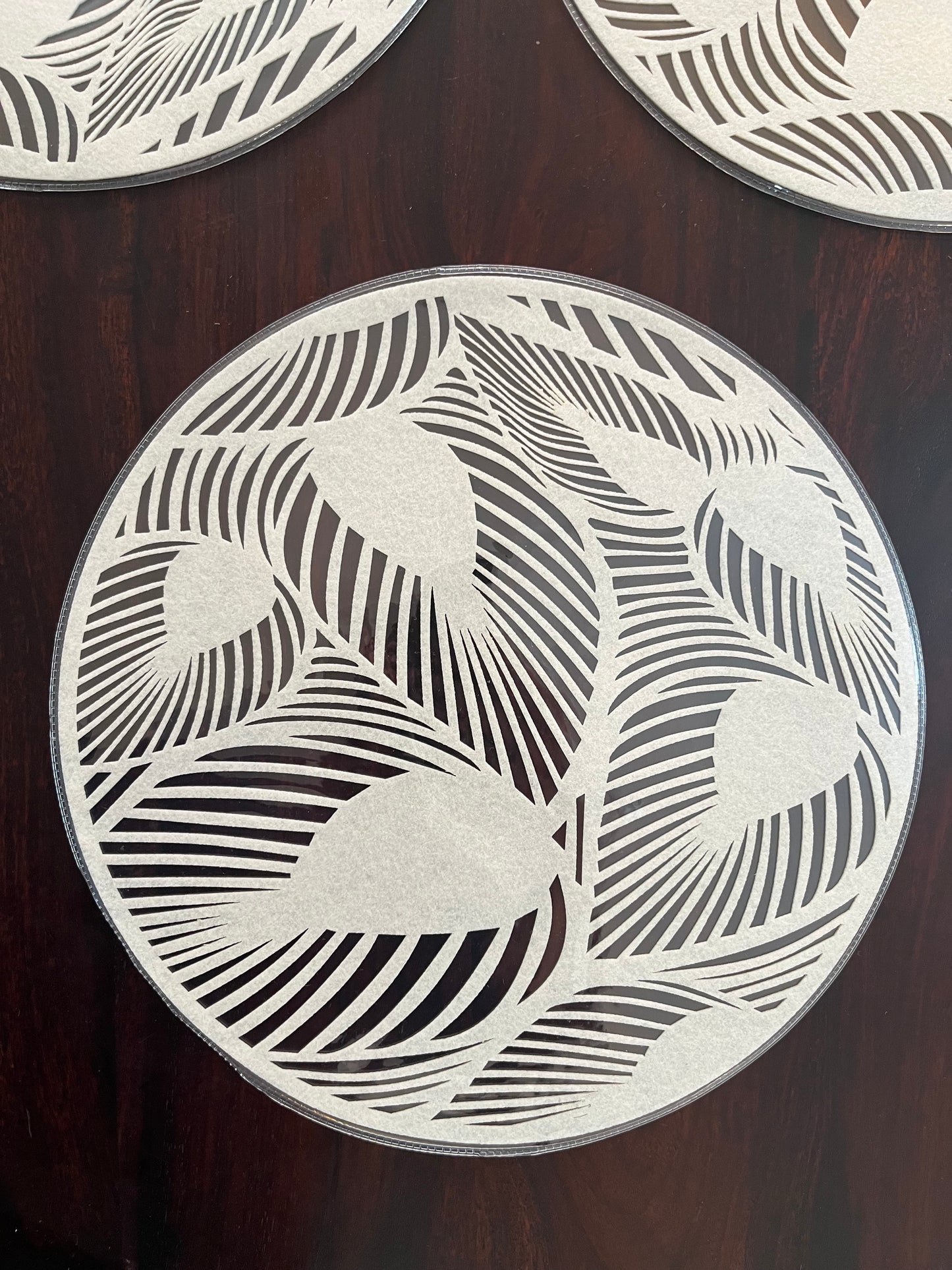 Set of 6 laminated round placemats featuring a modern leaf pattern, perfect for stylish table settings