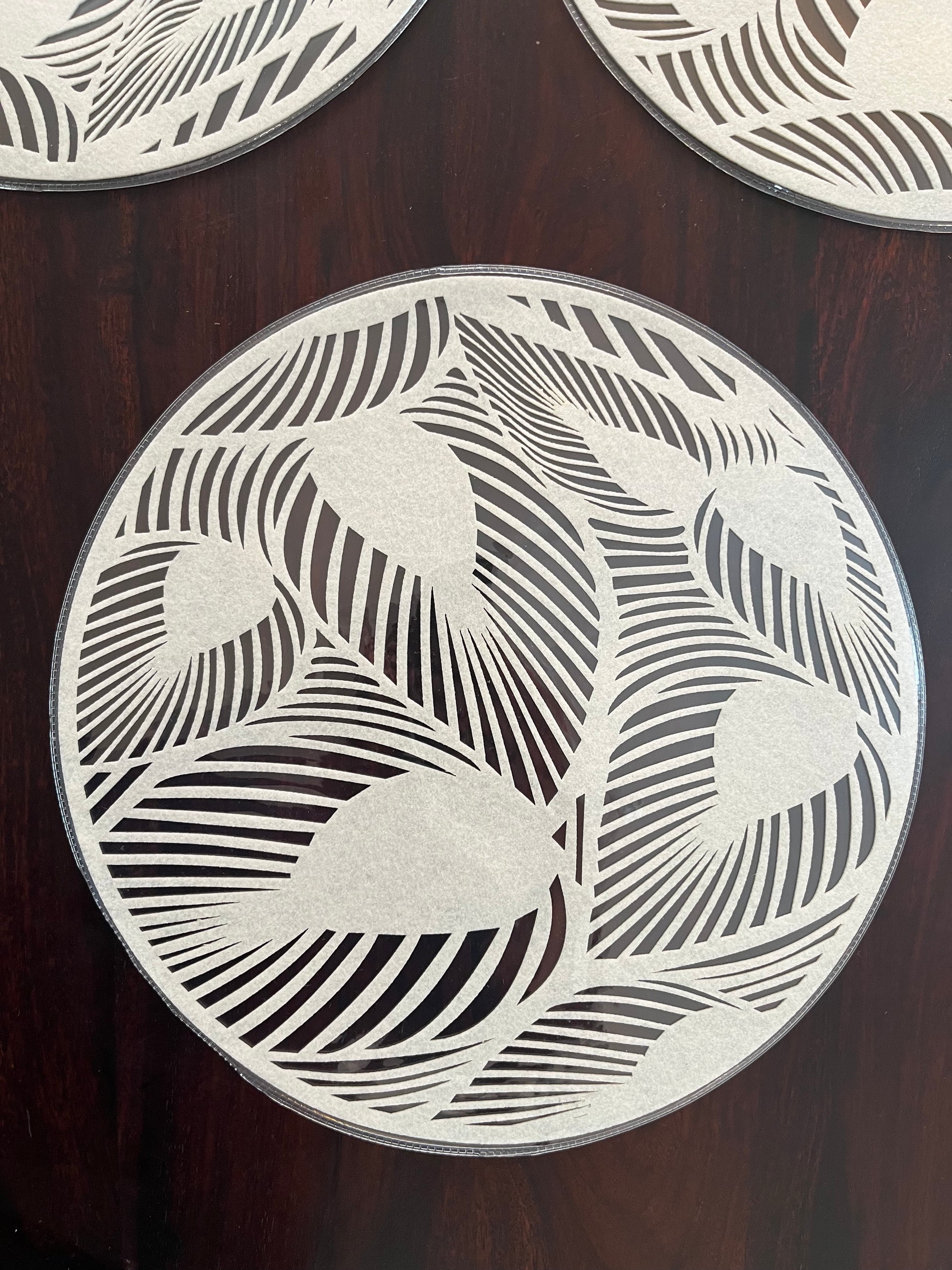 Set of 6 laminated round placemats featuring a modern leaf pattern, perfect for stylish table settings
