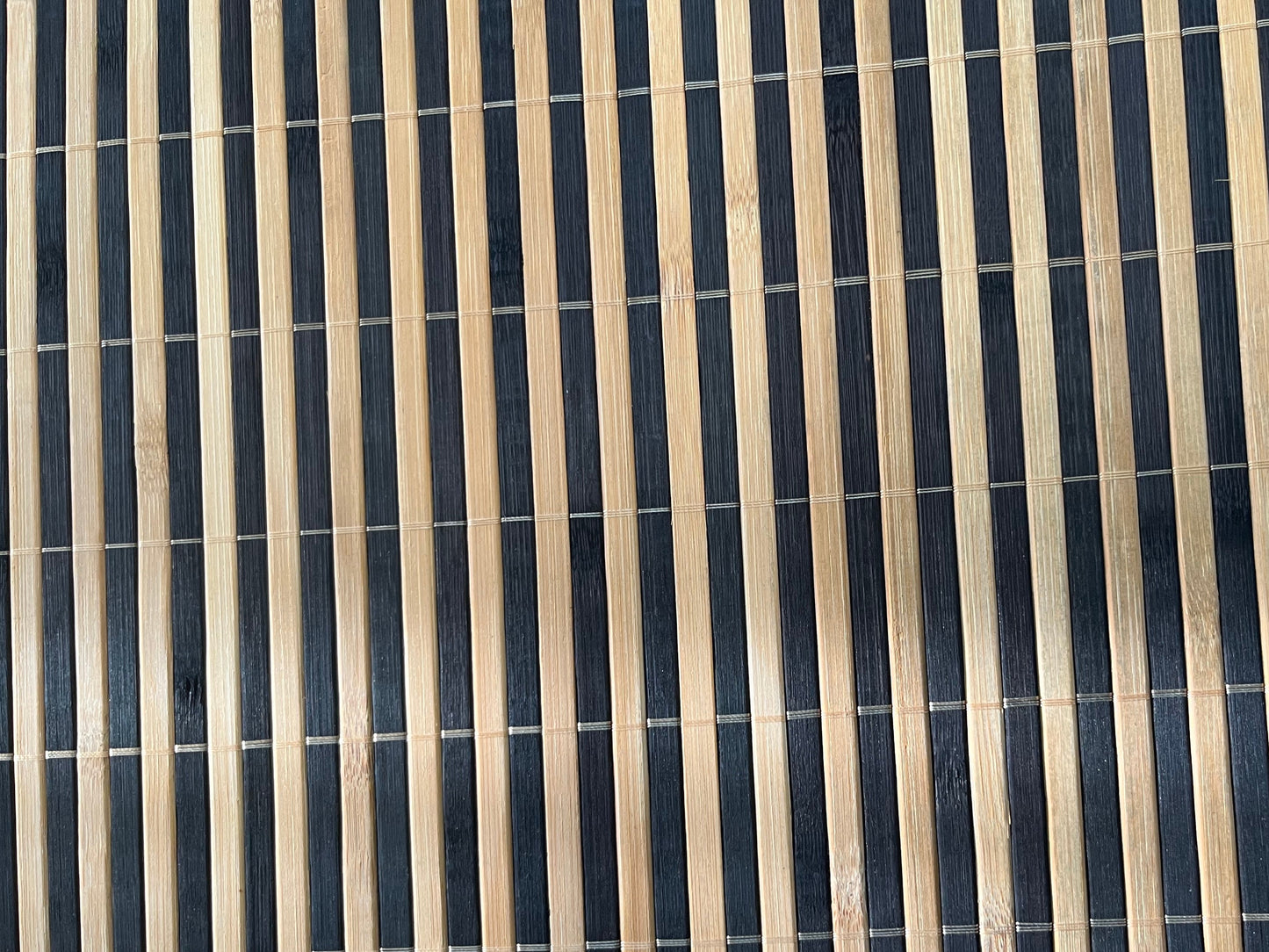 Close-up of bamboo woven placemat showcasing dark brown finish with natural striped detailing