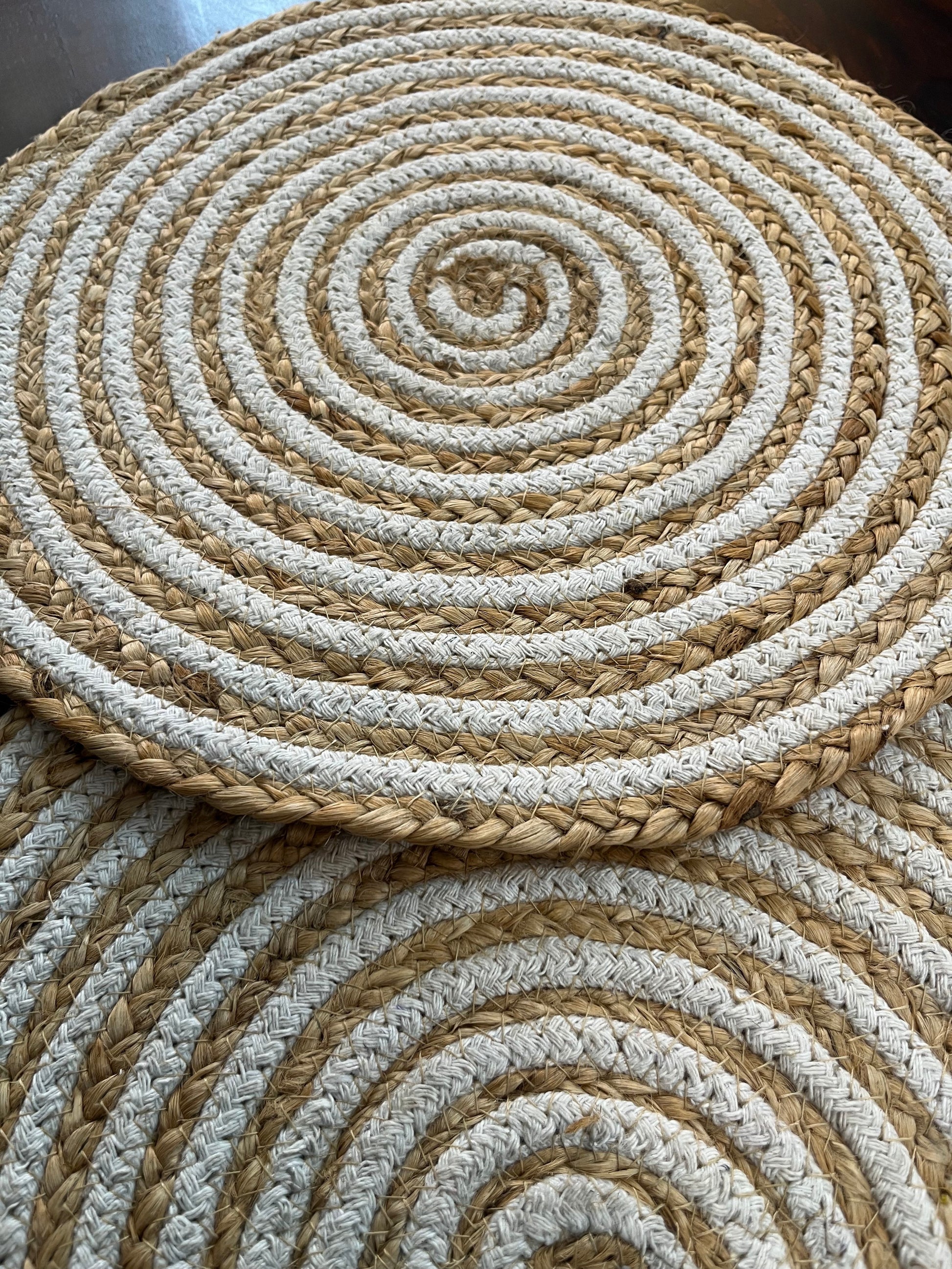 Close-up of round braided jute placemat showcasing natural fiber texture and white spiral pattern