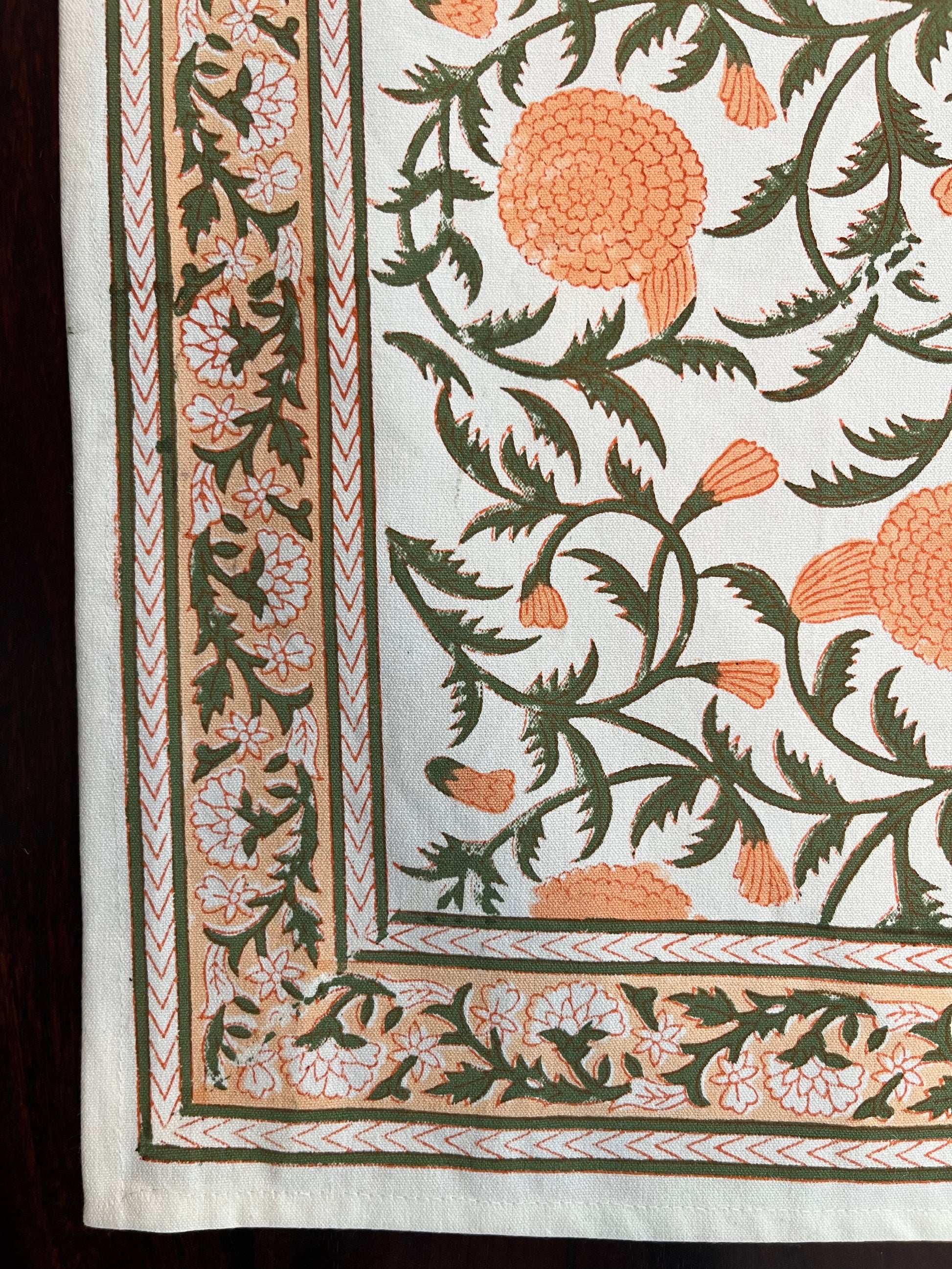 Close-up of cotton placemat showcasing delicate peach and forest green floral pattern with soft fabric texture