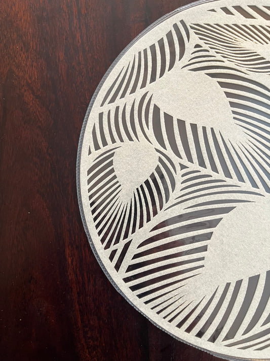 Close-up of laminated round placemat showcasing intricate modern leaf pattern and smooth finish