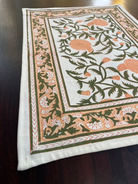 Charming dining table setup featuring cotton placemats with a peach and forest green floral design for a fresh, vibrant look