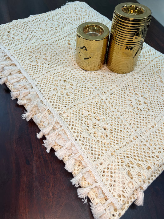 Beautifully styled dining table with a crocheted tablecloth featuring a diamond pattern and tassels in cream color
