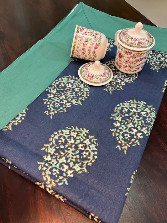 Beautifully styled dining table with a decorative navy blue table cover featuring a floral paisley pattern and a green border