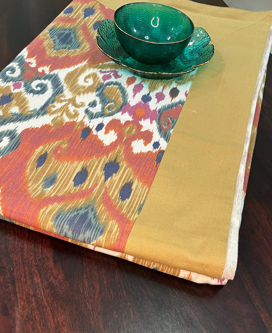Beautifully styled dining table with a decorative Ikat pattern tablecloth featuring a gold border and boho design