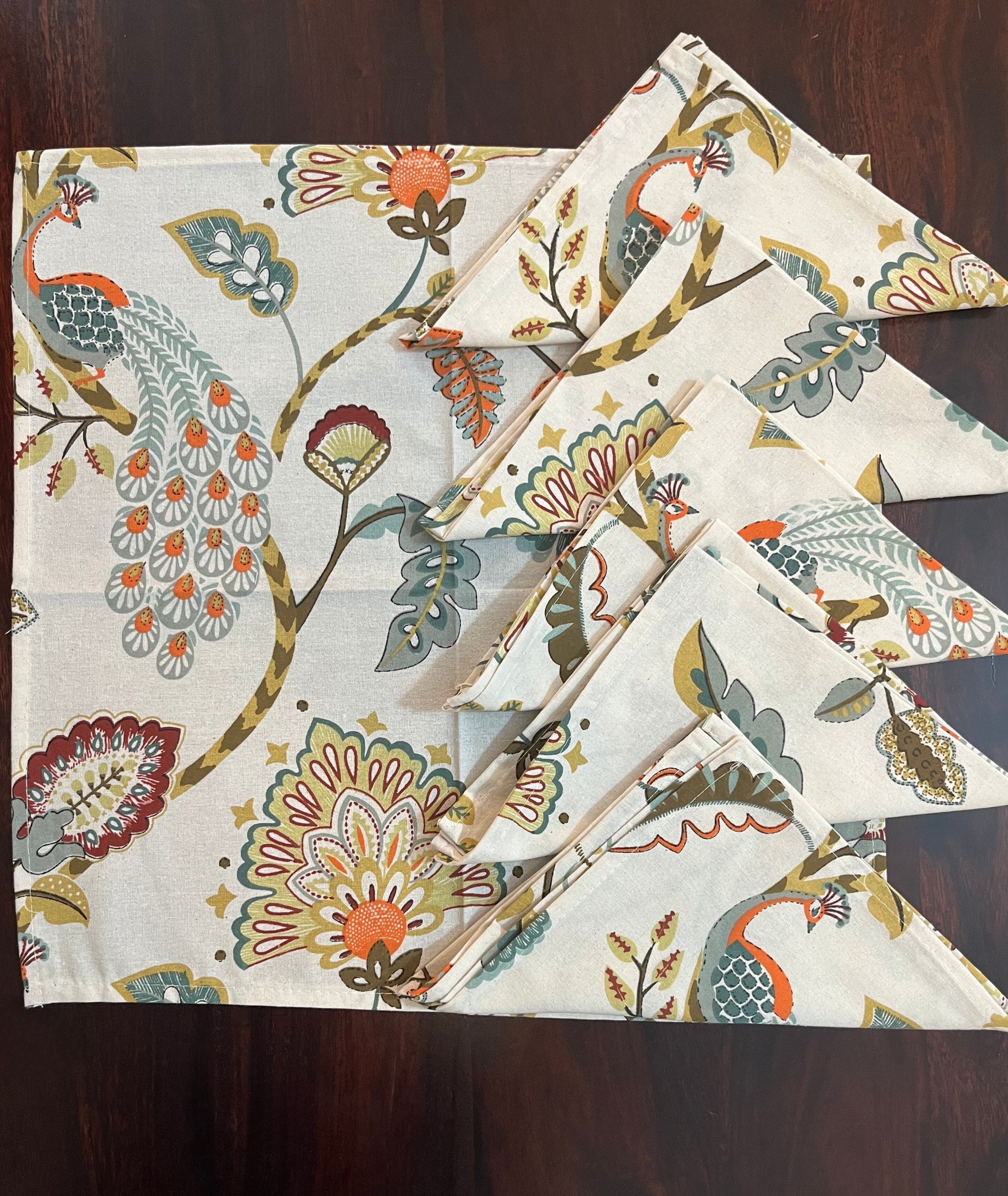 Beautifully folded decorative napkins with a peacock and floral motif, perfect for elegant table settings