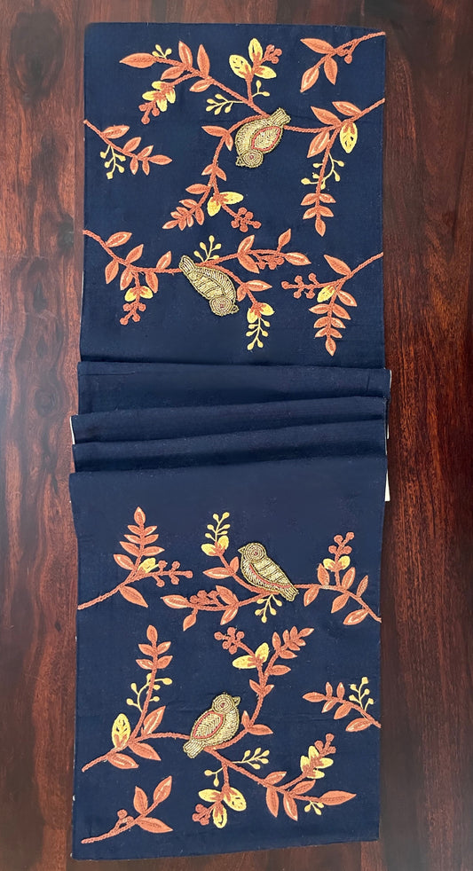 Beautifully styled dining table with a decorative table runner featuring embroidered and beaded birds and leaves