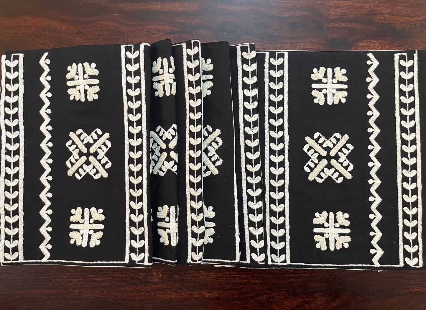 Beautifully styled dining table with a decorative table runner featuring geometric folk embroidery in black and white