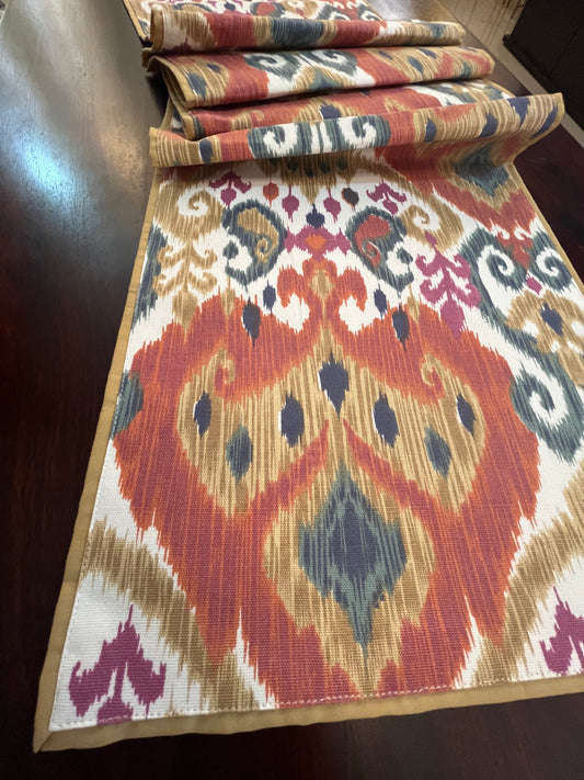 Beautifully styled dining table with a decorative table runner featuring an Ikat pattern in orange and blue with a multicolour boho design
