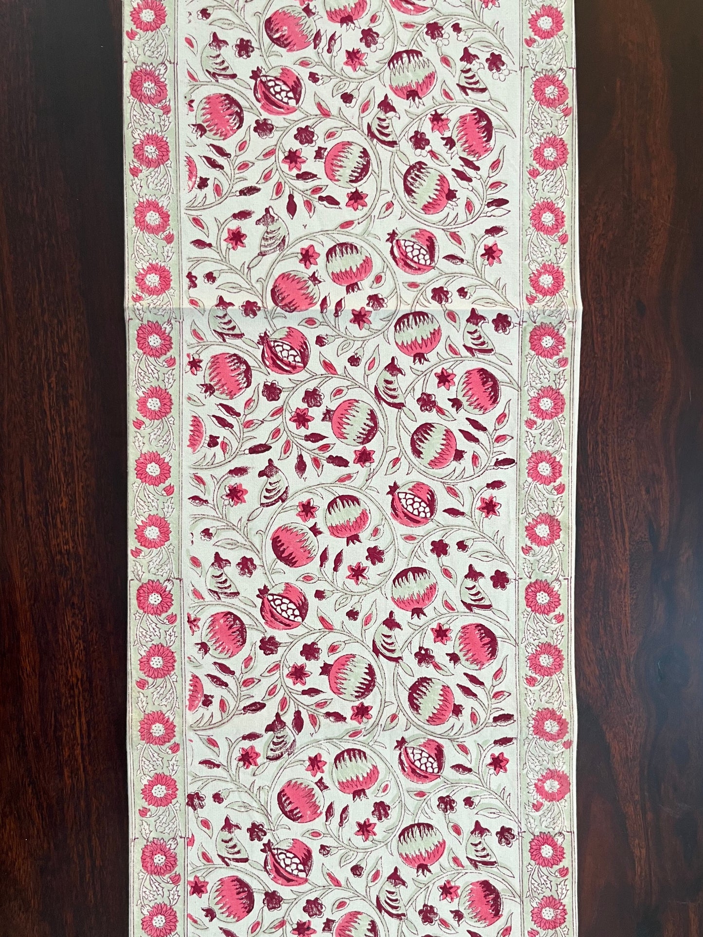 Beautifully styled dining table with a decorative table runner featuring a pink and white pomegranate floral pattern