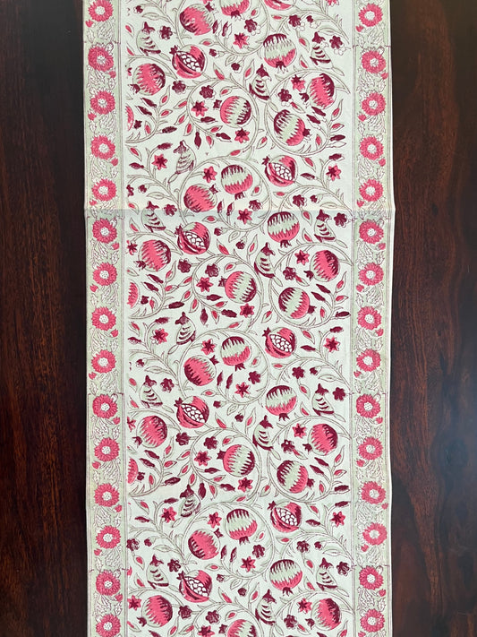 Beautifully styled dining table with a decorative table runner featuring a pink and white pomegranate floral pattern
