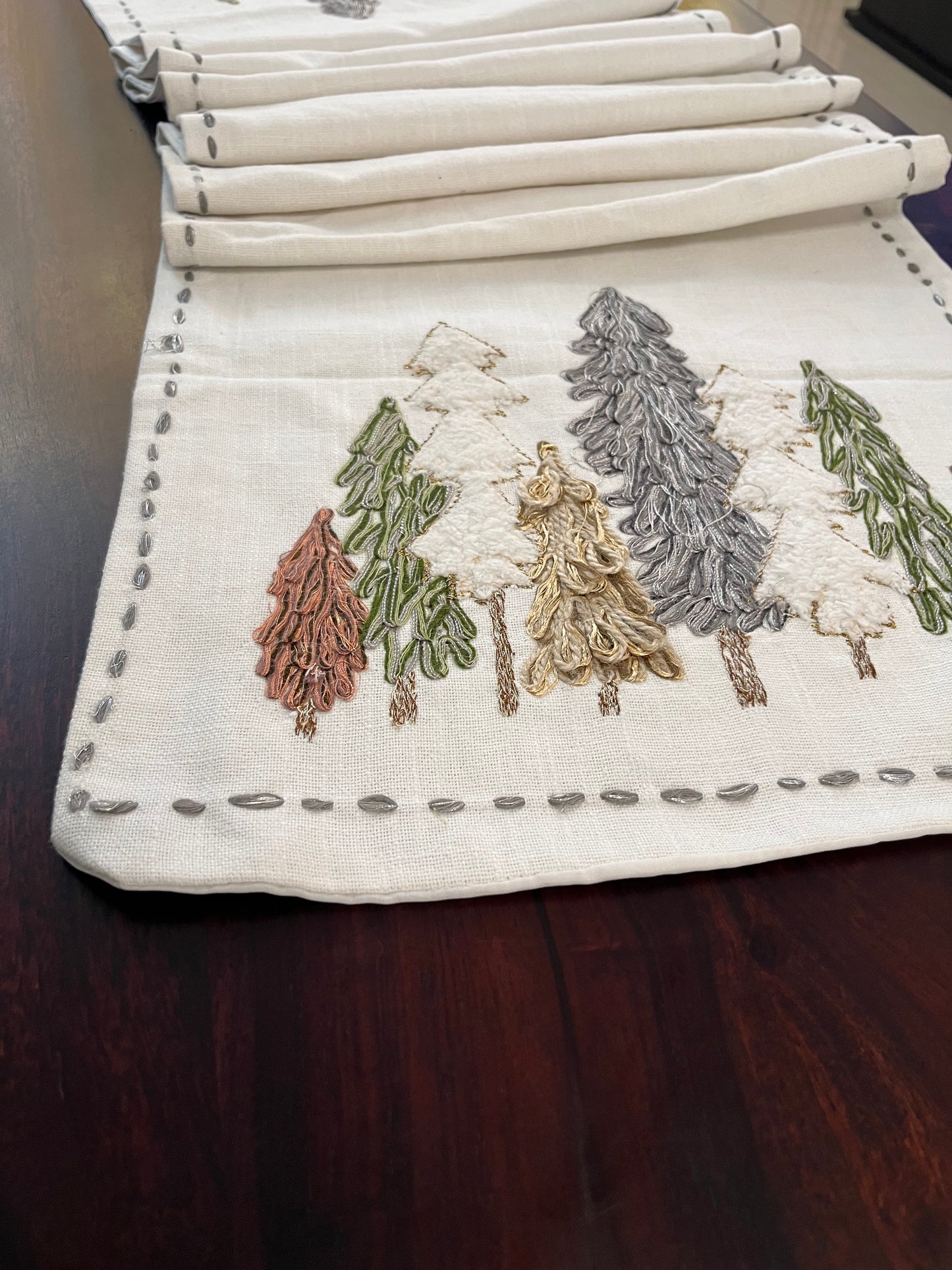 Beautifully styled dining table with a decorative winter forest table runner featuring embroidered pine trees