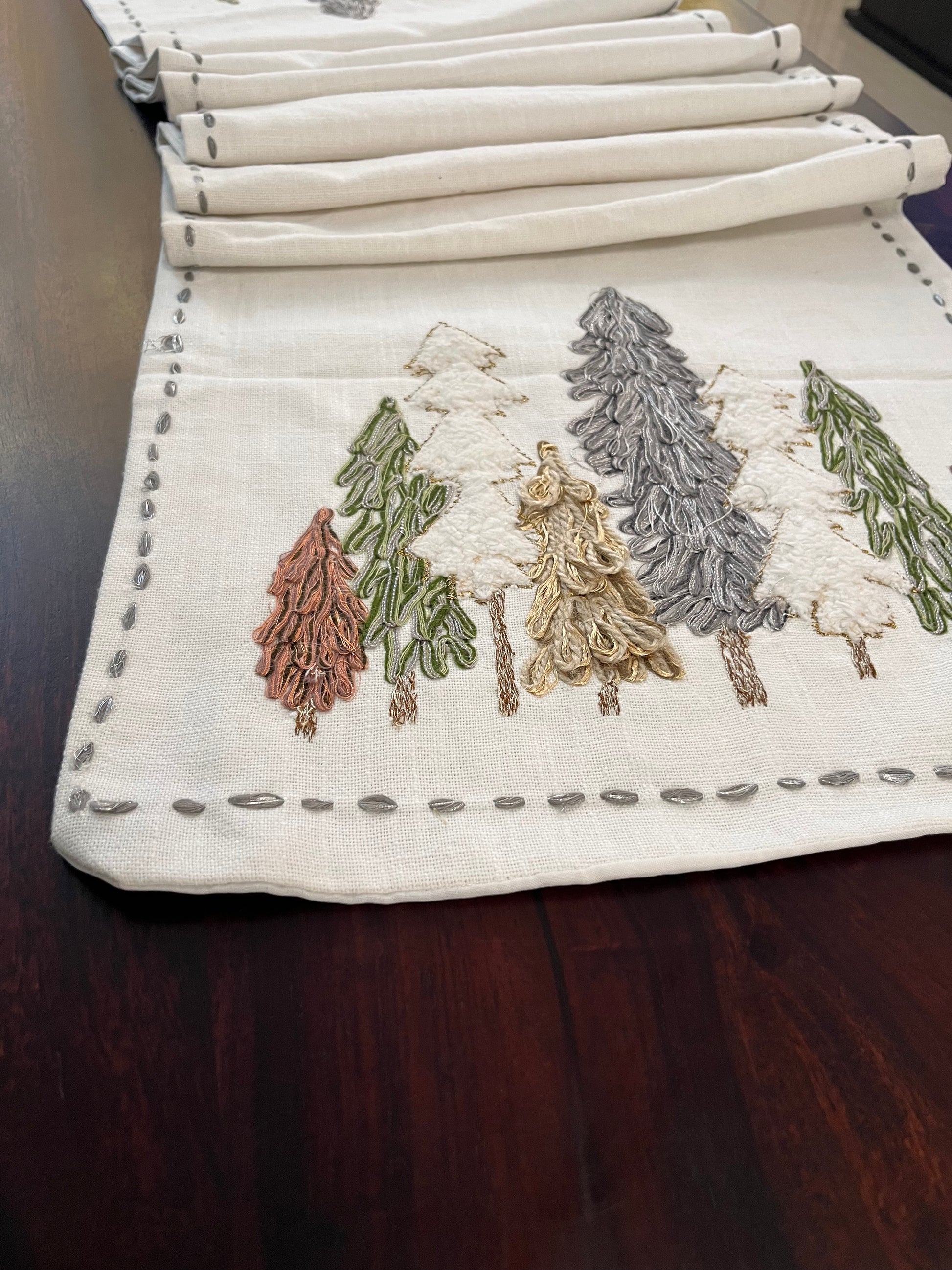 Beautifully styled dining table with a decorative winter forest table runner featuring embroidered pine trees