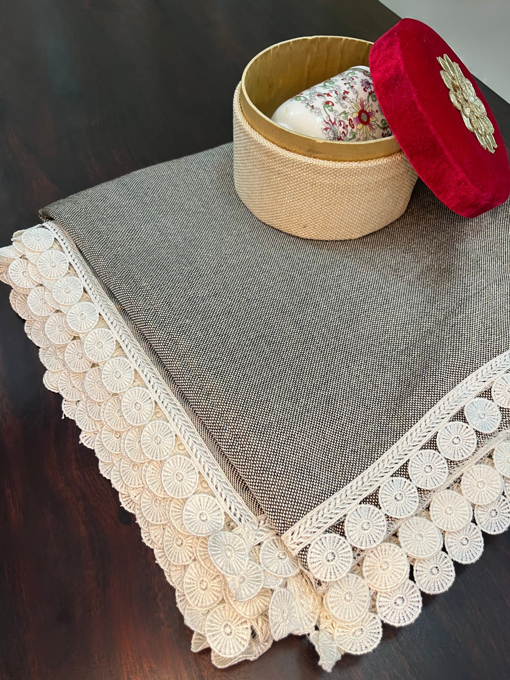 Beautifully styled dining table featuring an elegant grey textured table cover with white lace trim and a scalloped border