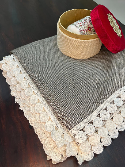 Beautifully styled dining table featuring an elegant grey textured table cover with white lace trim and a scalloped border