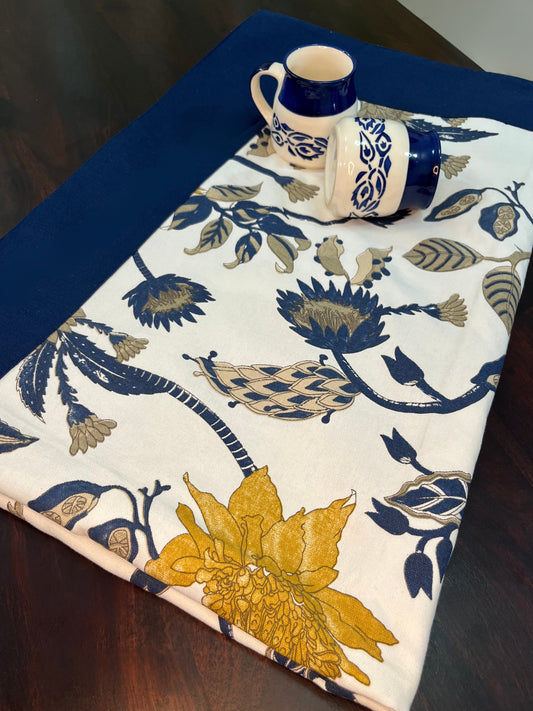 Beautifully styled dining table with a floral tablecloth featuring a navy blue border and yellow-blue flower pattern