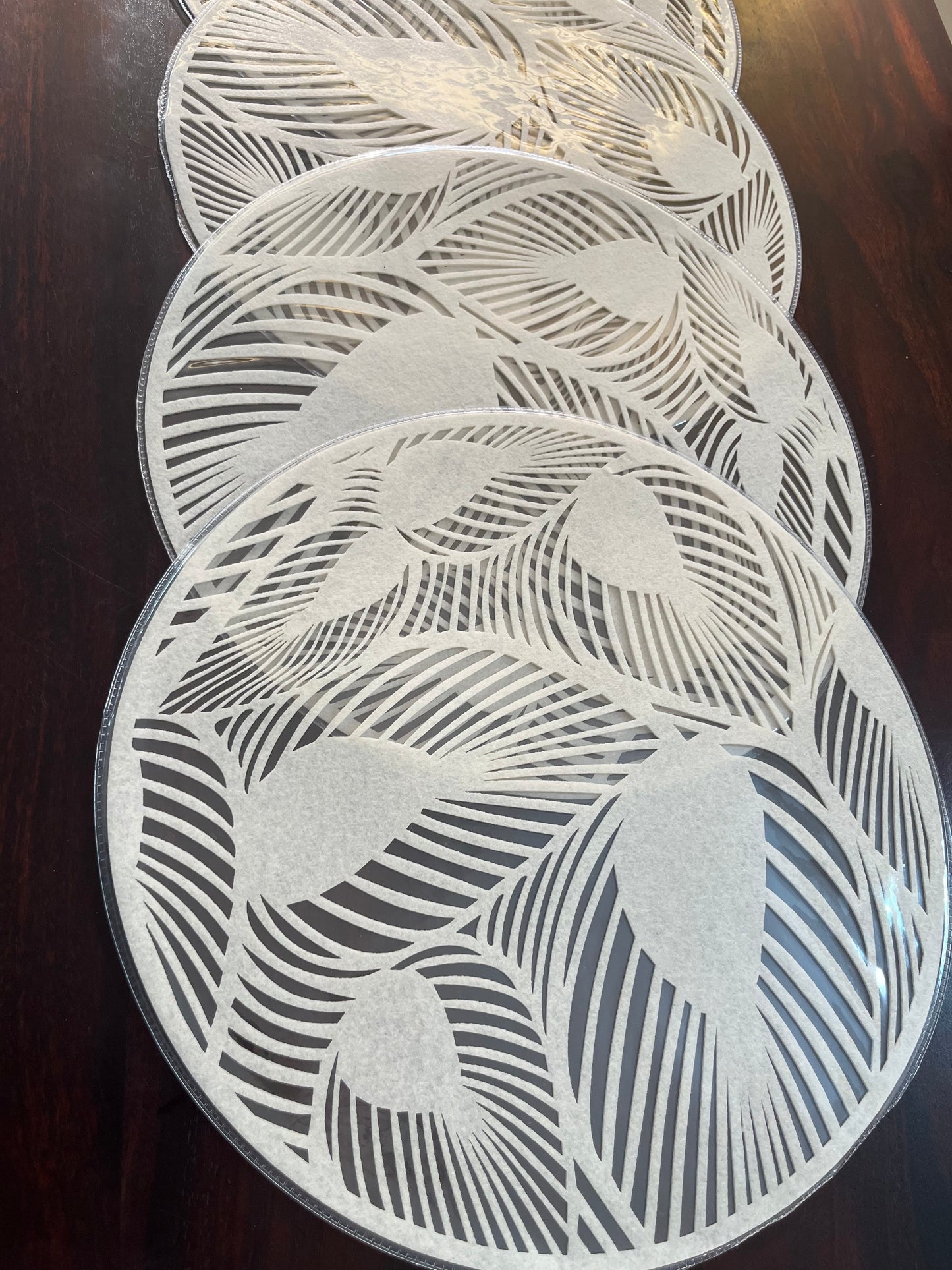 Elegant dining setup featuring laminated round placemats with a modern leaf pattern for a chic look