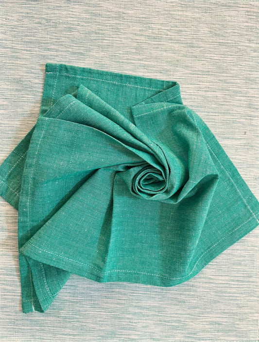 Beautiful dining table setup featuring teal green woven placemats and matching napkins for a sophisticated look