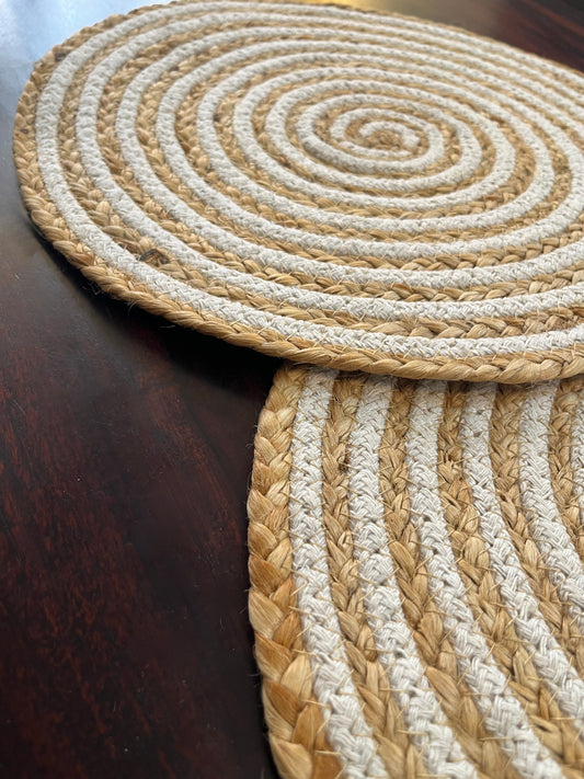 Beautifully styled dining table featuring round braided jute placemats with a natural and white spiral design